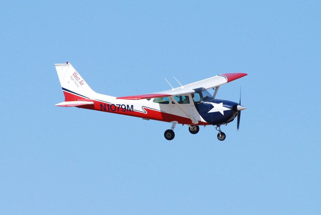 A student pilot beside a training aircraft with a logbook