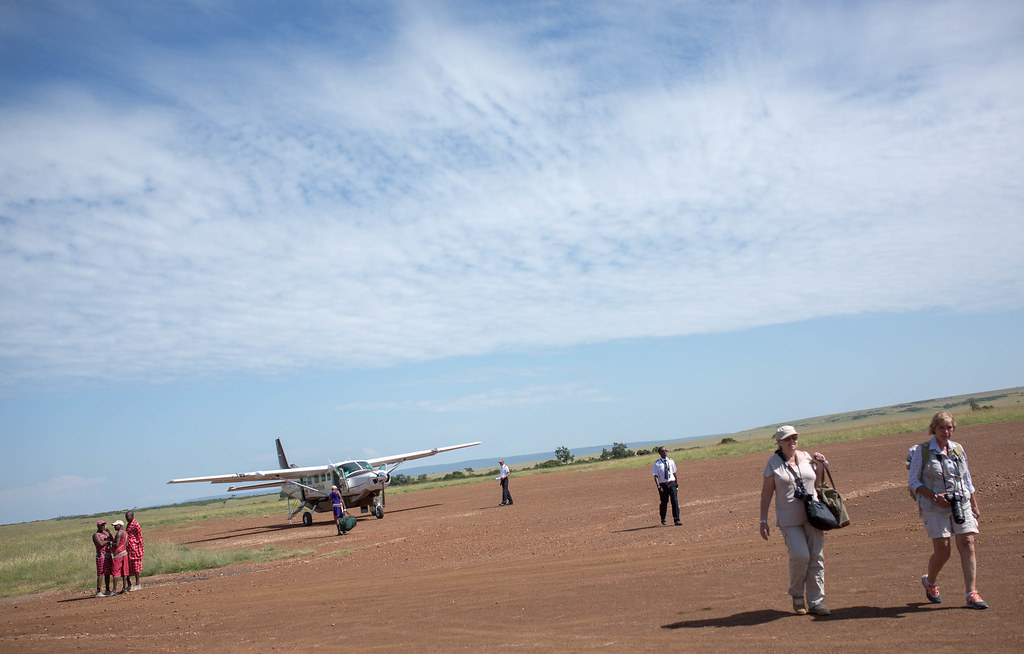 A light aircraft on a grass and dirt airstrip in East African savanna
